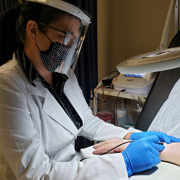 Woman giving electology procedure with mask and face shield